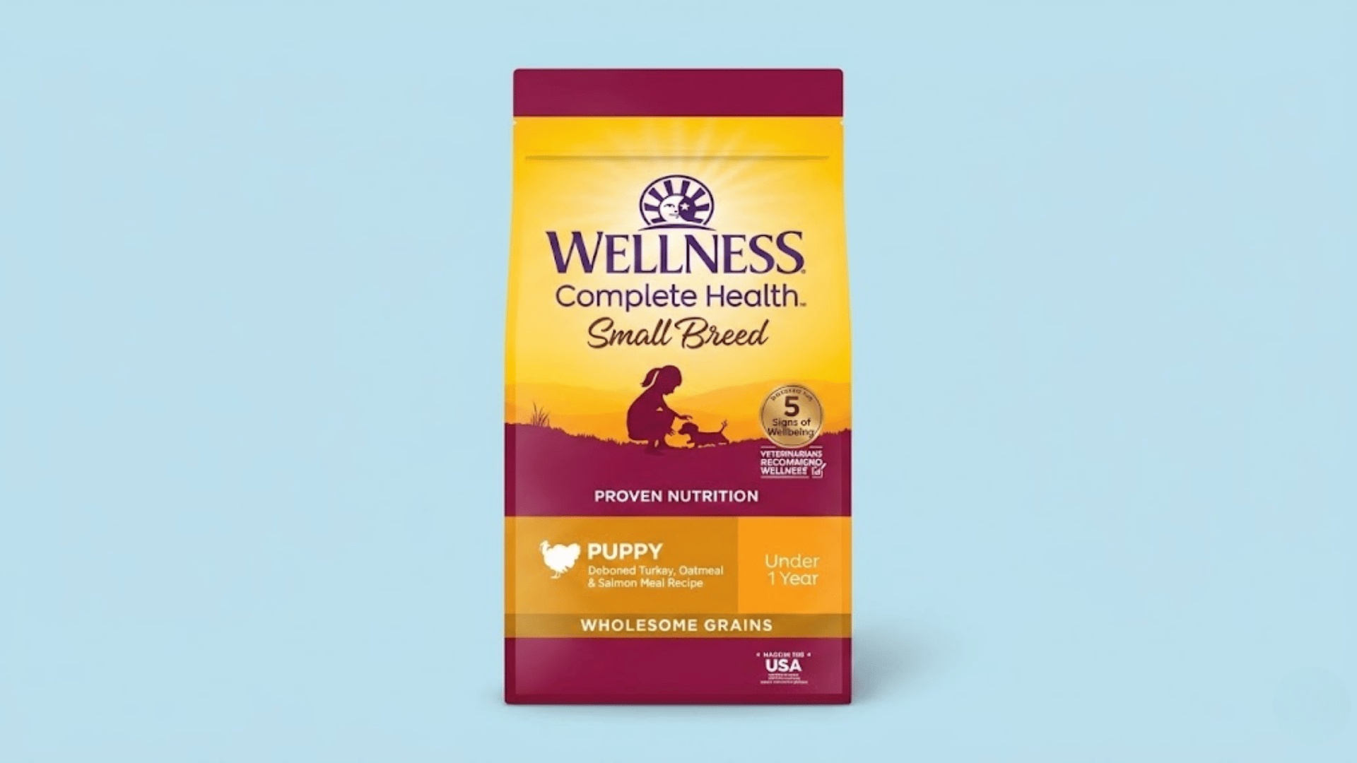 bag of wellness complete health small breed puppy food on a light blue background