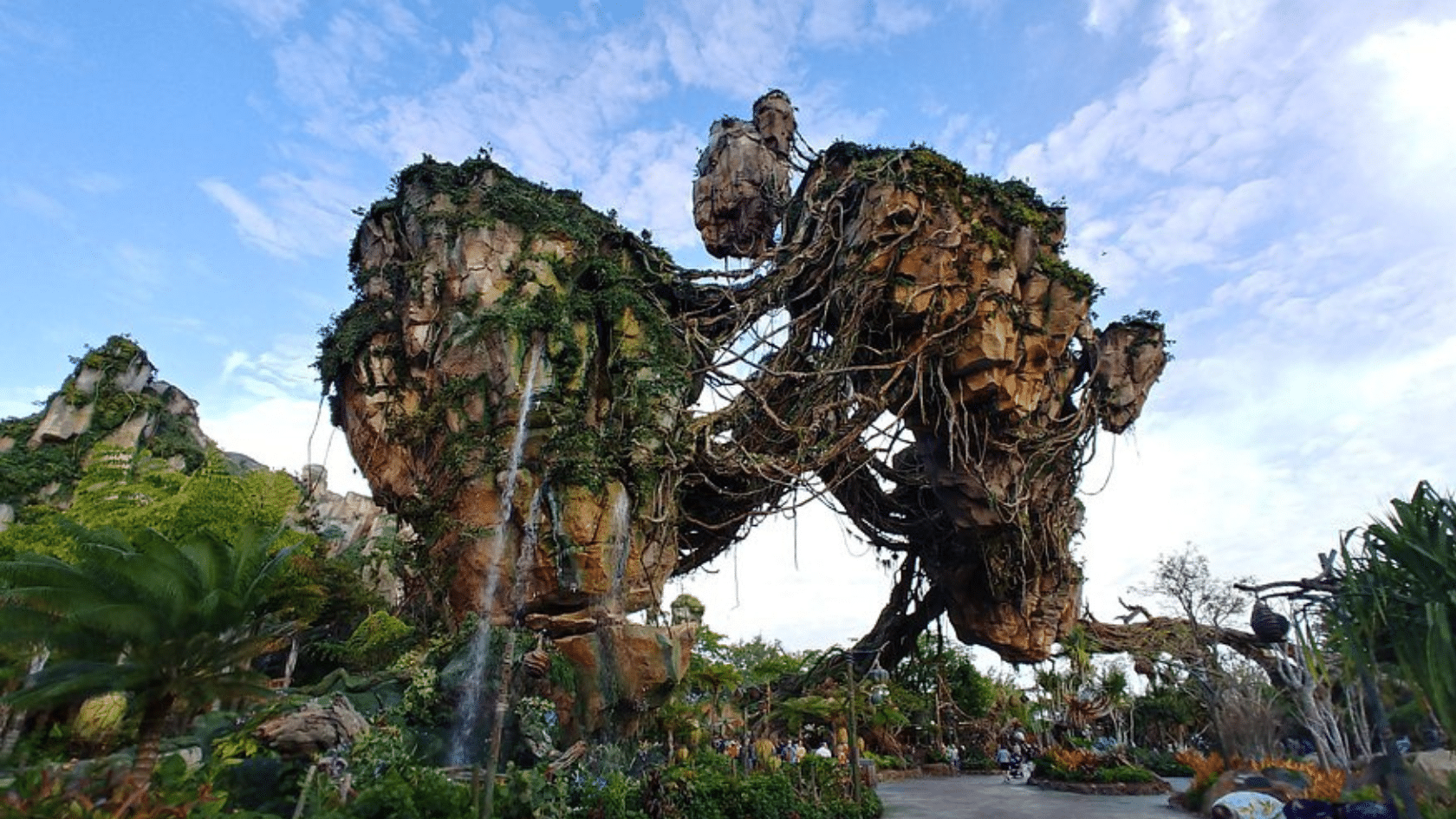 floating rock formations covered in vines with waterfalls above a lush pathway beneath a bright blue sky