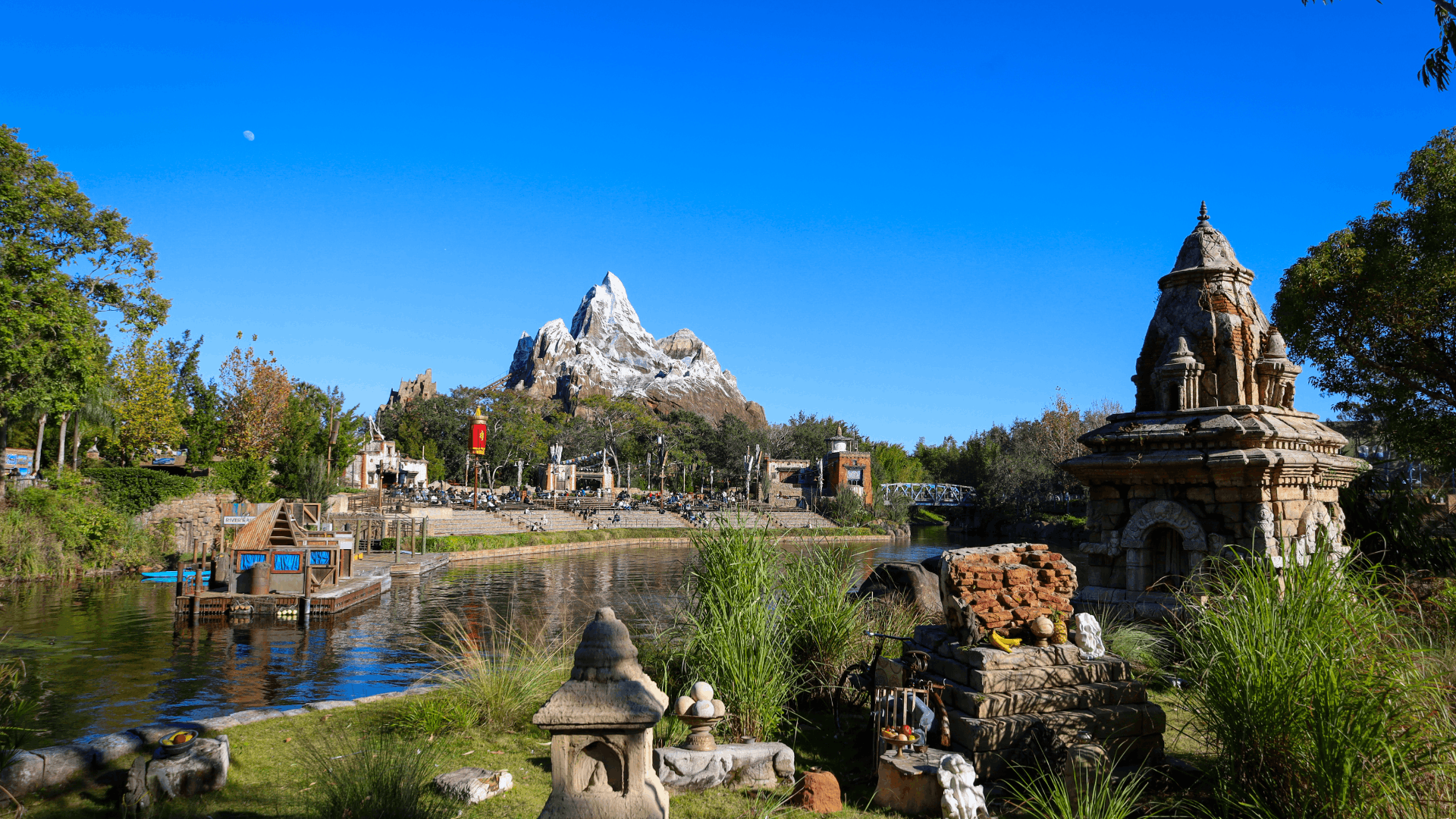 lush gardens and ancient temple ruins surround a tranquil waterway in asia at animal kingdom