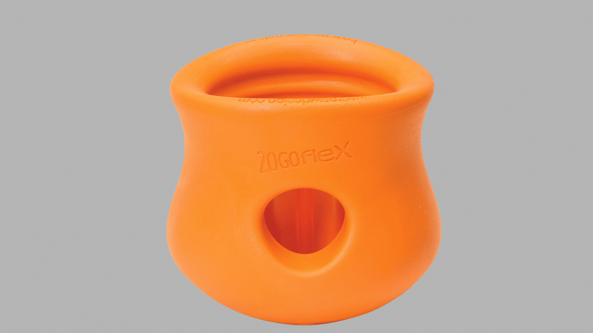 orange rubber dog treat toy with rounded hourglass shape and side opening designed for dispensing treats and interactive play