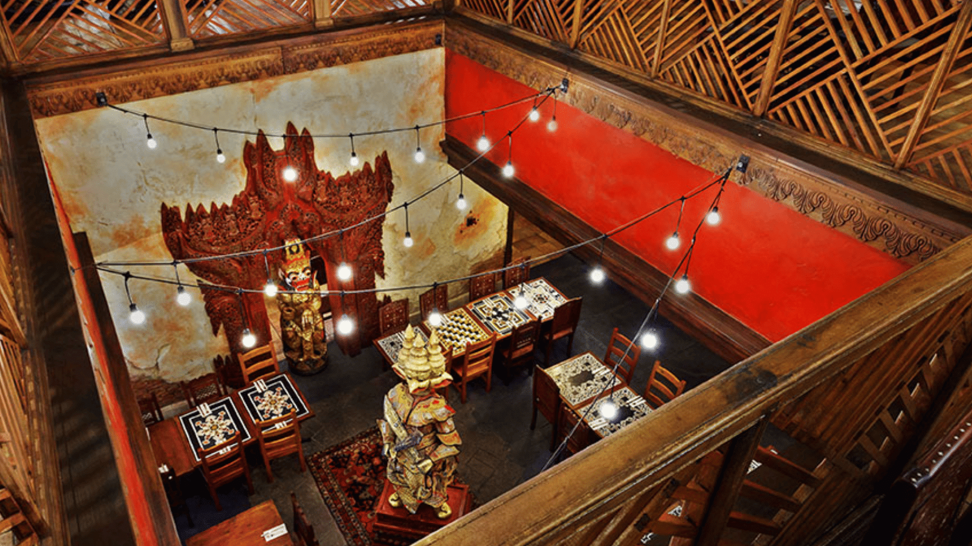 ornate dining area features carved statues wooden railings string lights and themed seating inside animal kingdom restaurant