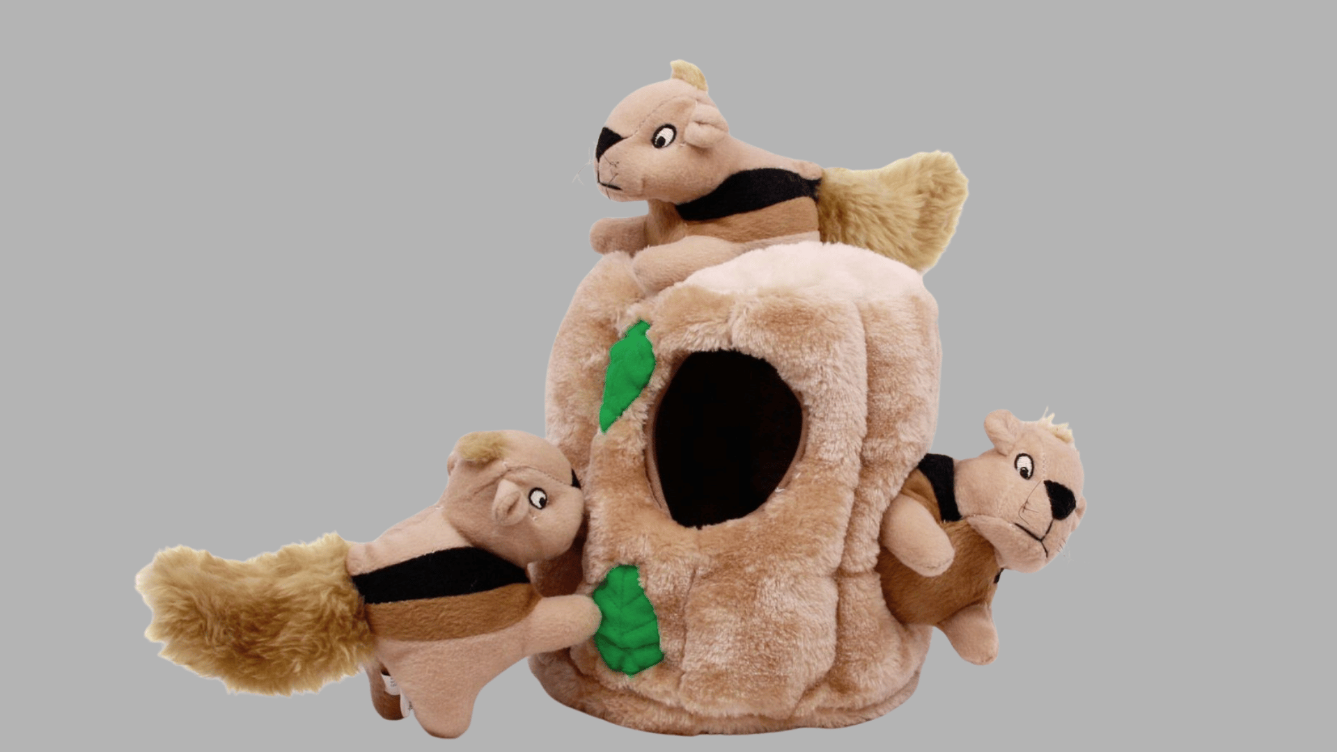 plush tree stump dog puzzle toy with three stuffed squirrel toys partially tucked into openings around the soft fabric base
