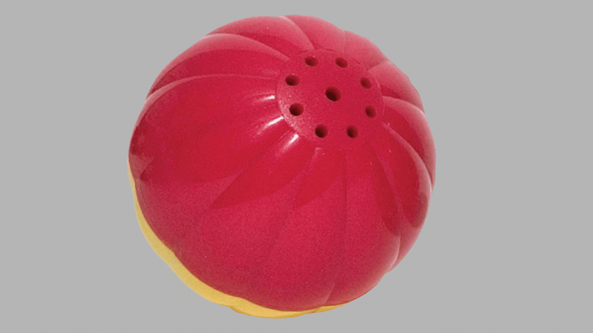 red and yellow rubber dog treat ball with ridged surface and multiple small openings designed for dispensing treats during play