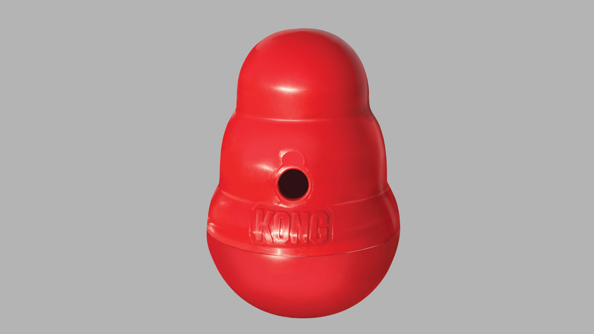 red kong dog toy with rounded stacked shape and center hole standing upright on a plain background