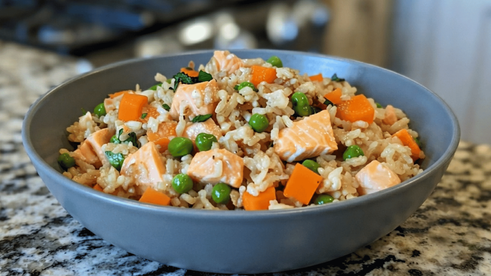 bowl of salmon rice with peas carrots and herbs served on a granite countertop as a fresh balanced homemade meal