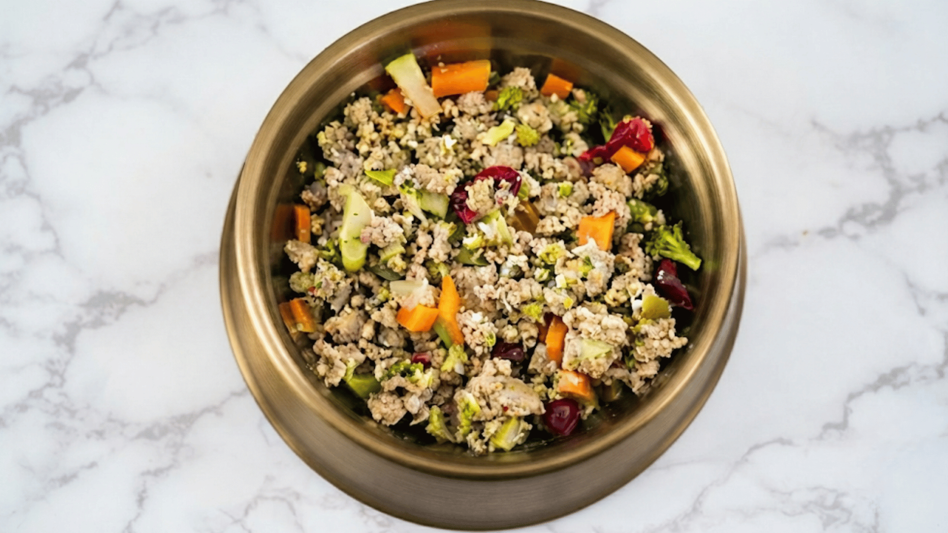 metal bowl filled with ground turkey broccoli carrots cabbage and vegetables served as a balanced homemade meal on a marble countertop